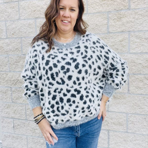 Add a bit of wildness to your style. This black and white leopard print sweater is the perfect way to add a touch of fun to your wardrobe. With its wide sleeves and soft, cozy fabric, it's perfect for chilly days. Match it with your favorite jeans or dress it up with a skirt. No matter how you wear it, you'll love the leopard print sweater.  Details Leopard Love Relax Fit Wide Sleeves Comfy and Cozy Color Black and white with gray trim